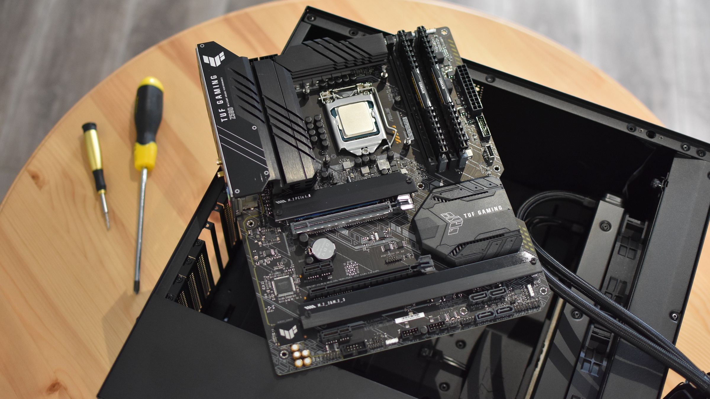 An Asus TUF Gaming Z590-Plus WiFi motherboard on top of an open PC case.