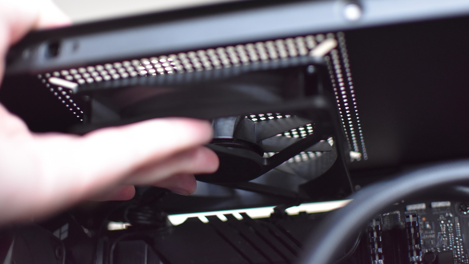 A 120mm case fan being positioned into the top fan slot of a PC case.