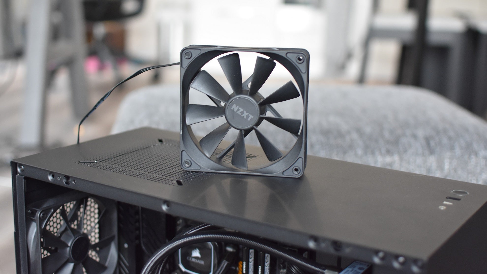 An NZXT case fan stood on top of an open PC case.