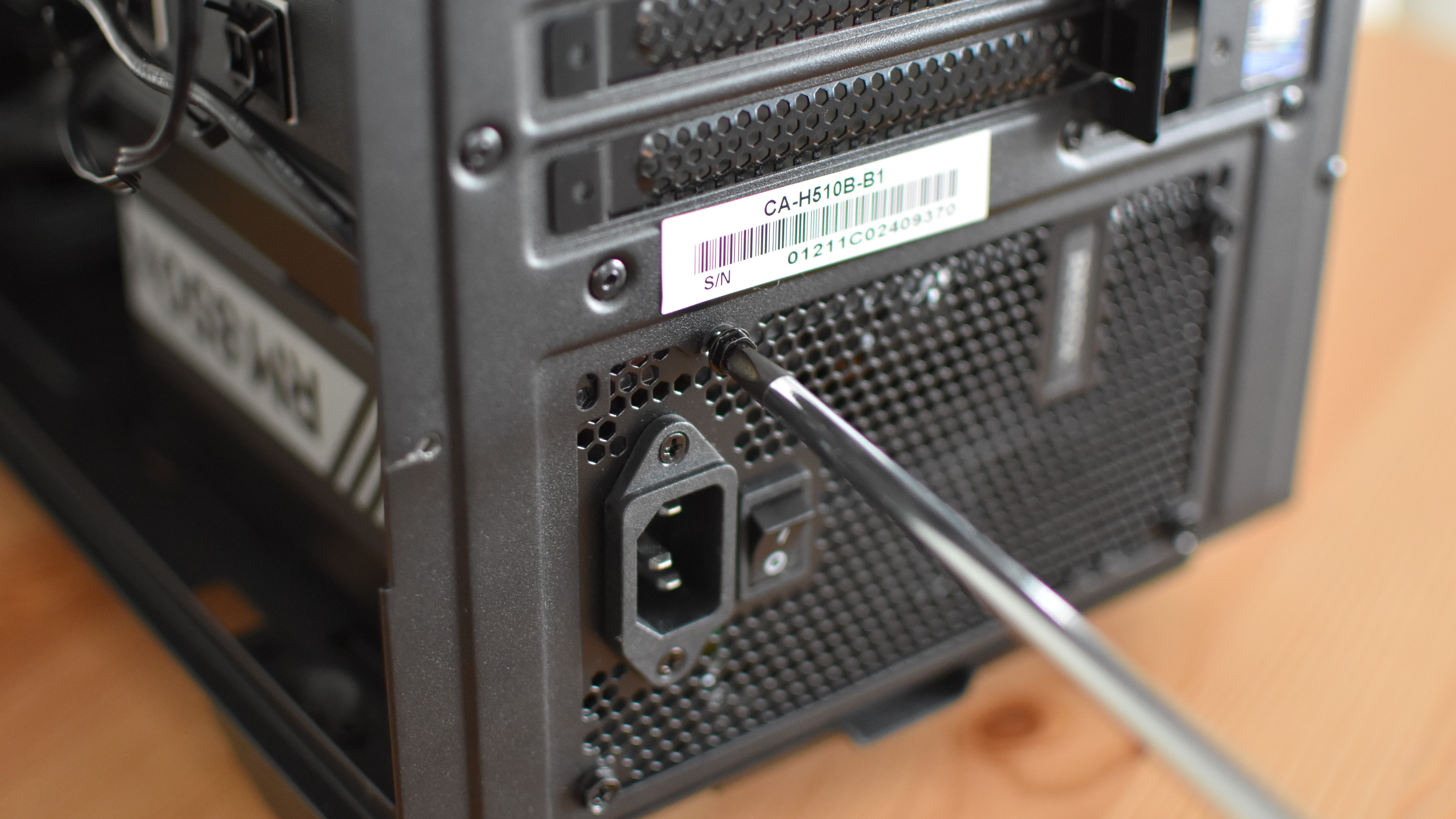 A PSU being fixed in position by tightening the PC's mounting screws.