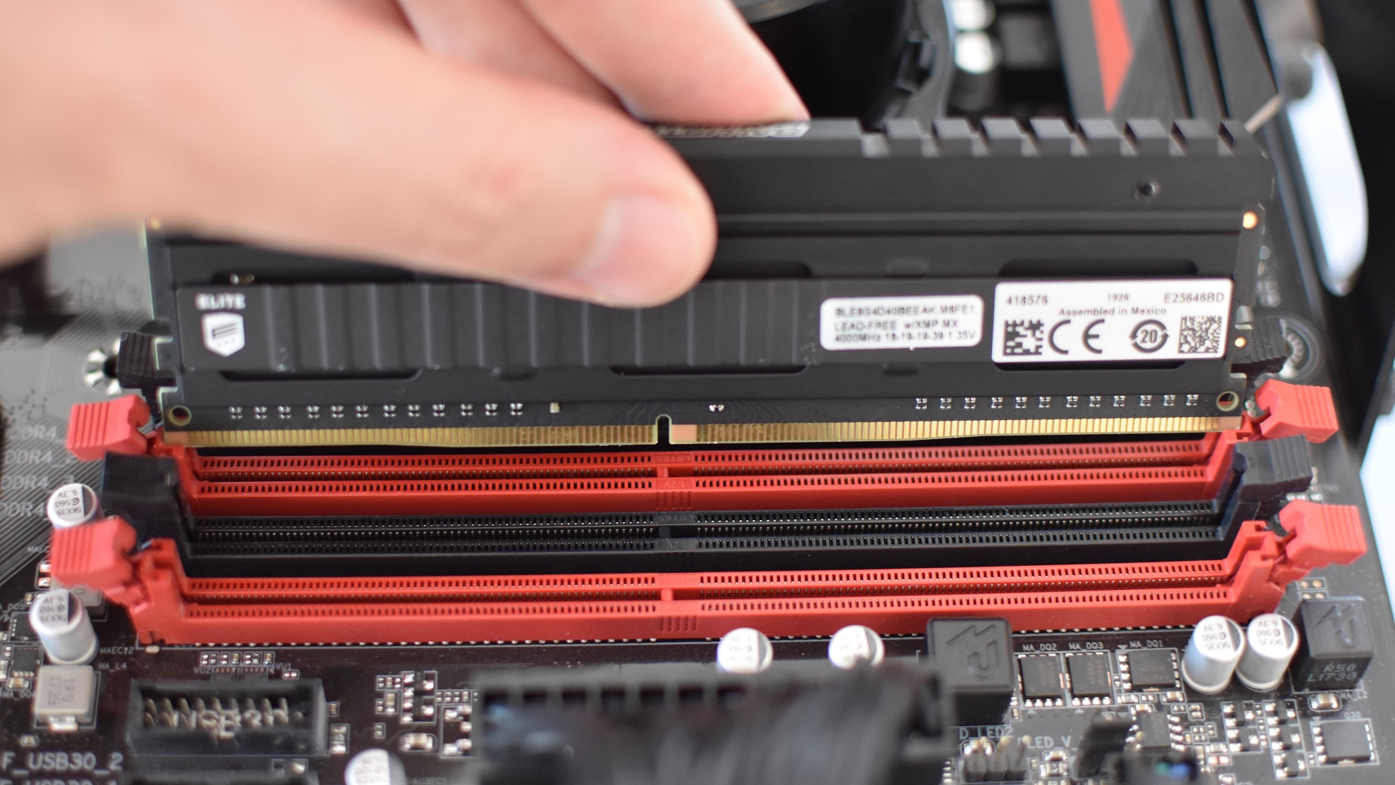 A stick of DDR4 RAM is lined up with its motherboard slot, shortly before it's pushed in.