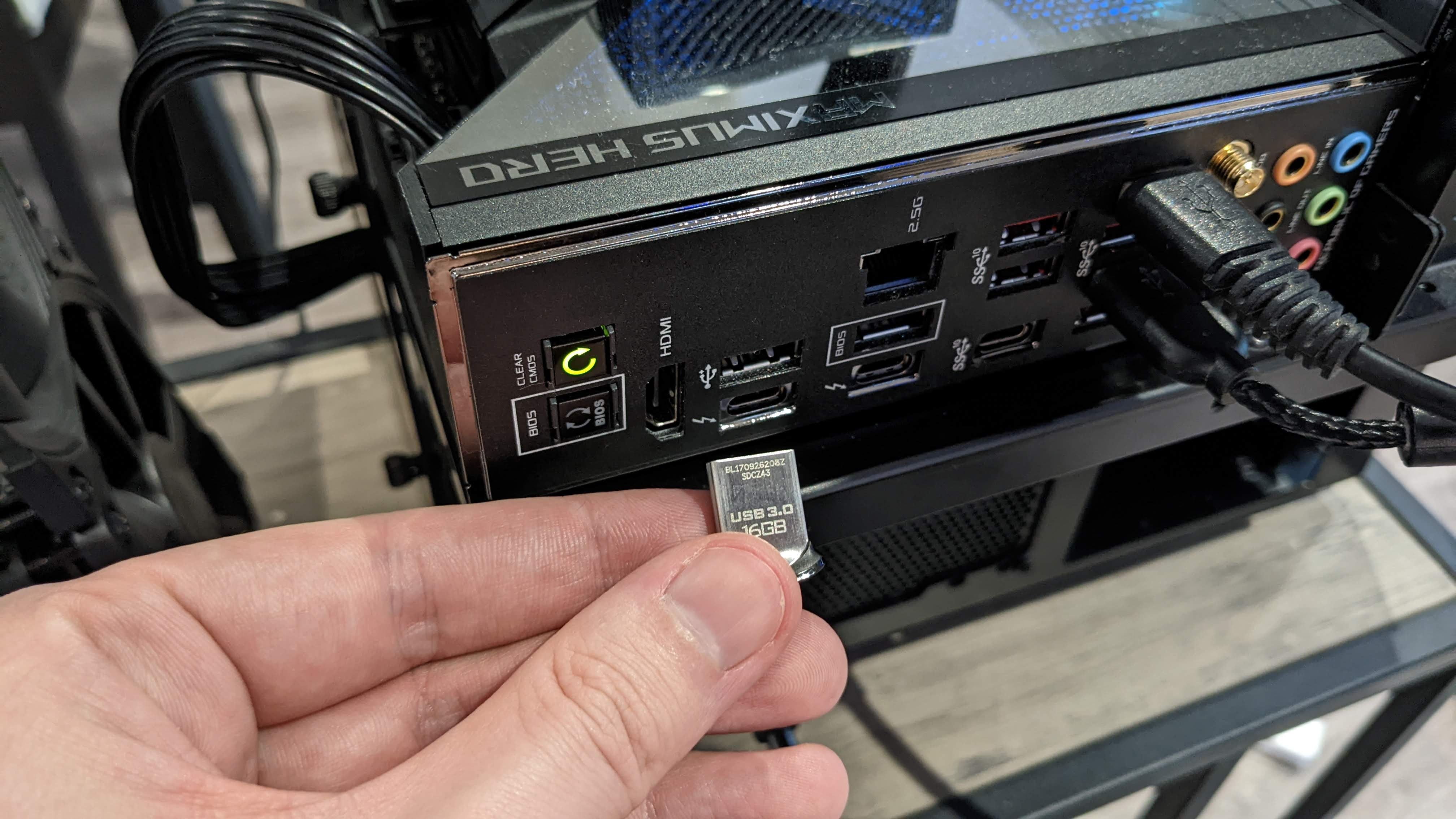 A small USB drive being inserted into a spare slot on a motherboard's rear I/O panel.