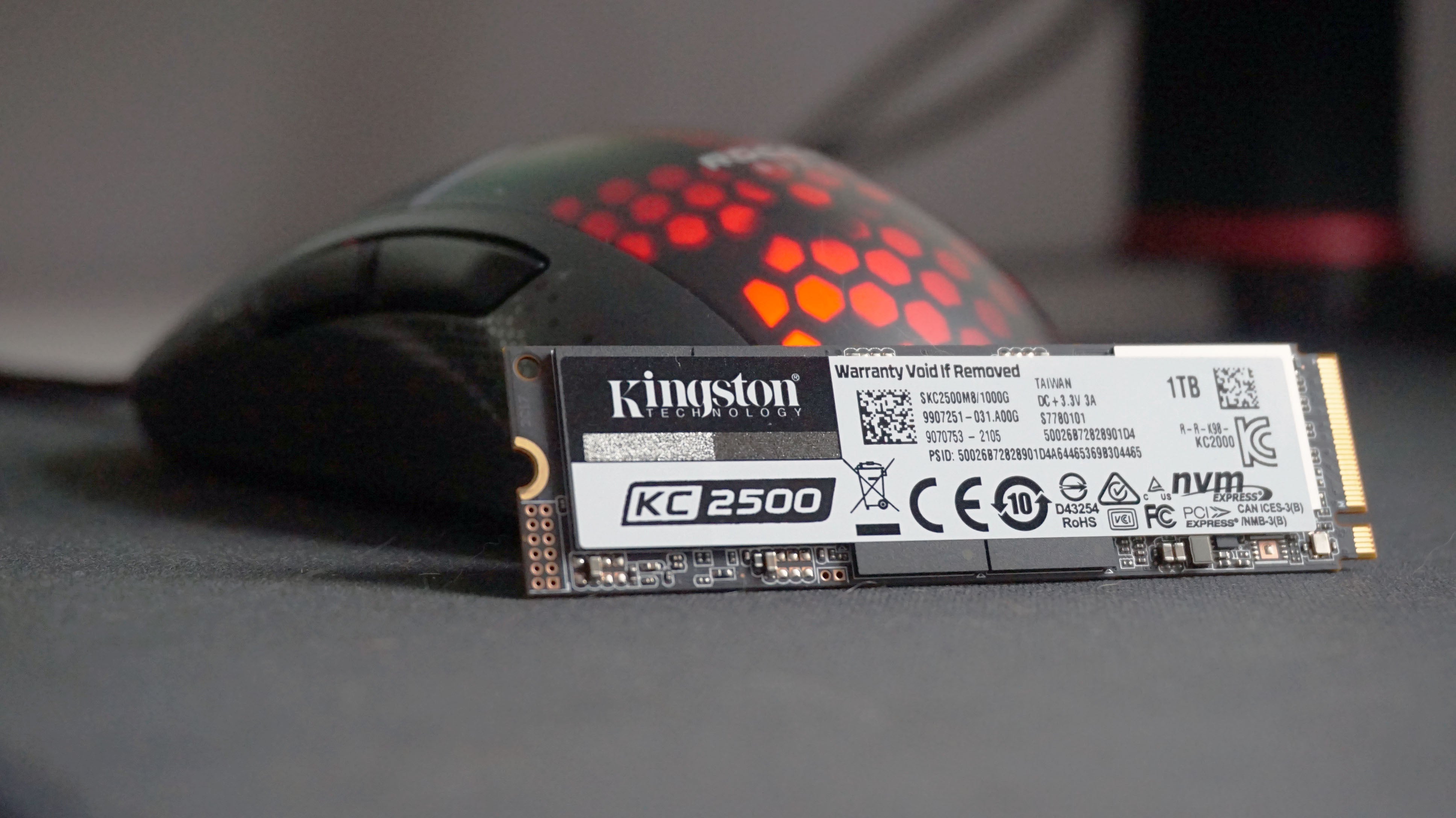 A photo of the Kingston KC2500 SSD in front of an RGB gaming mouse
