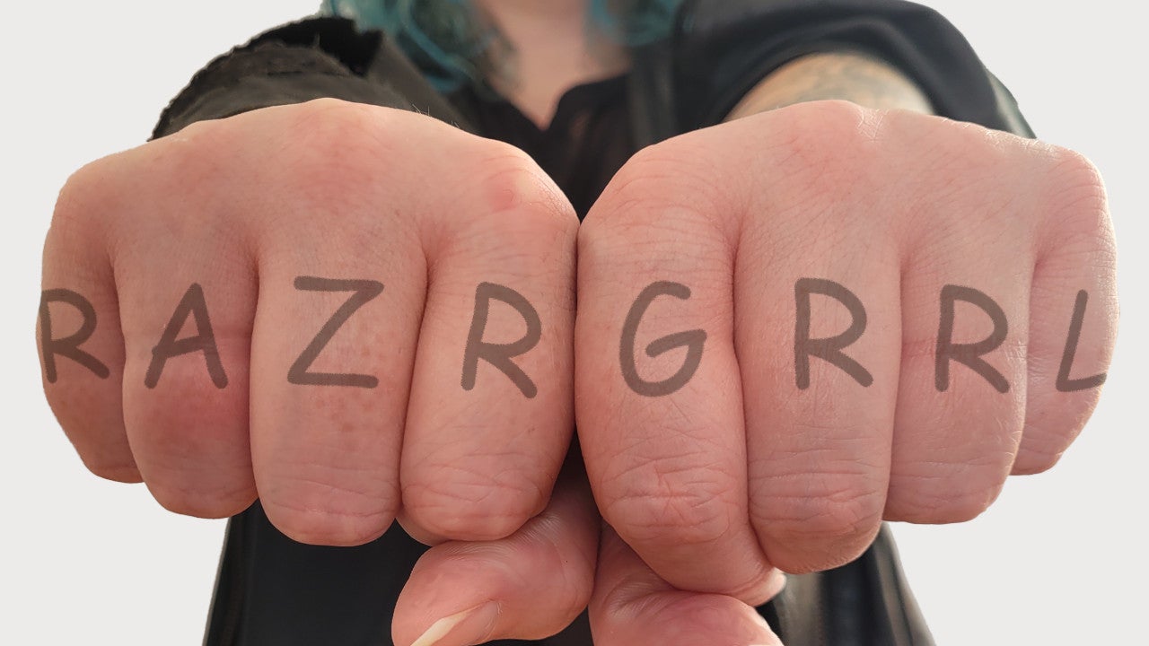 Outstretched fists displaying a mock-up knuckle tattoo: RAZRGRRL.