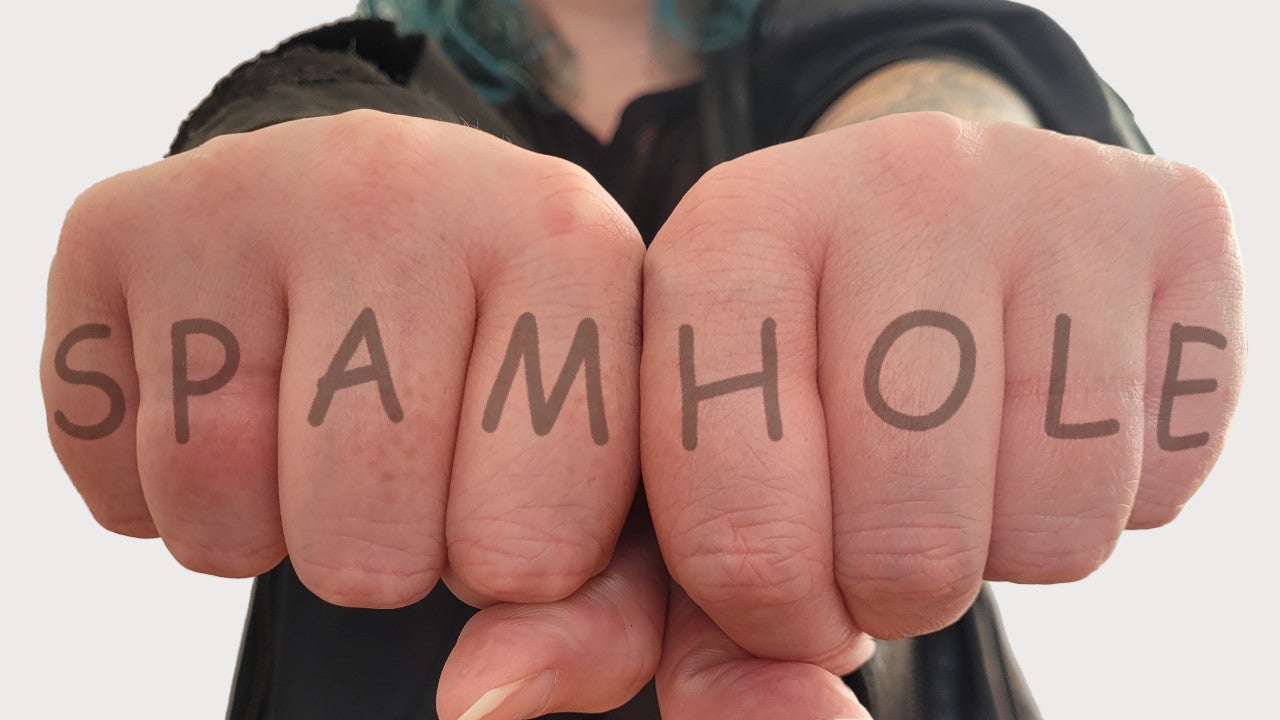 Outstretched fists displaying a mock-up knuckle tattoo: SPAMHOLE.