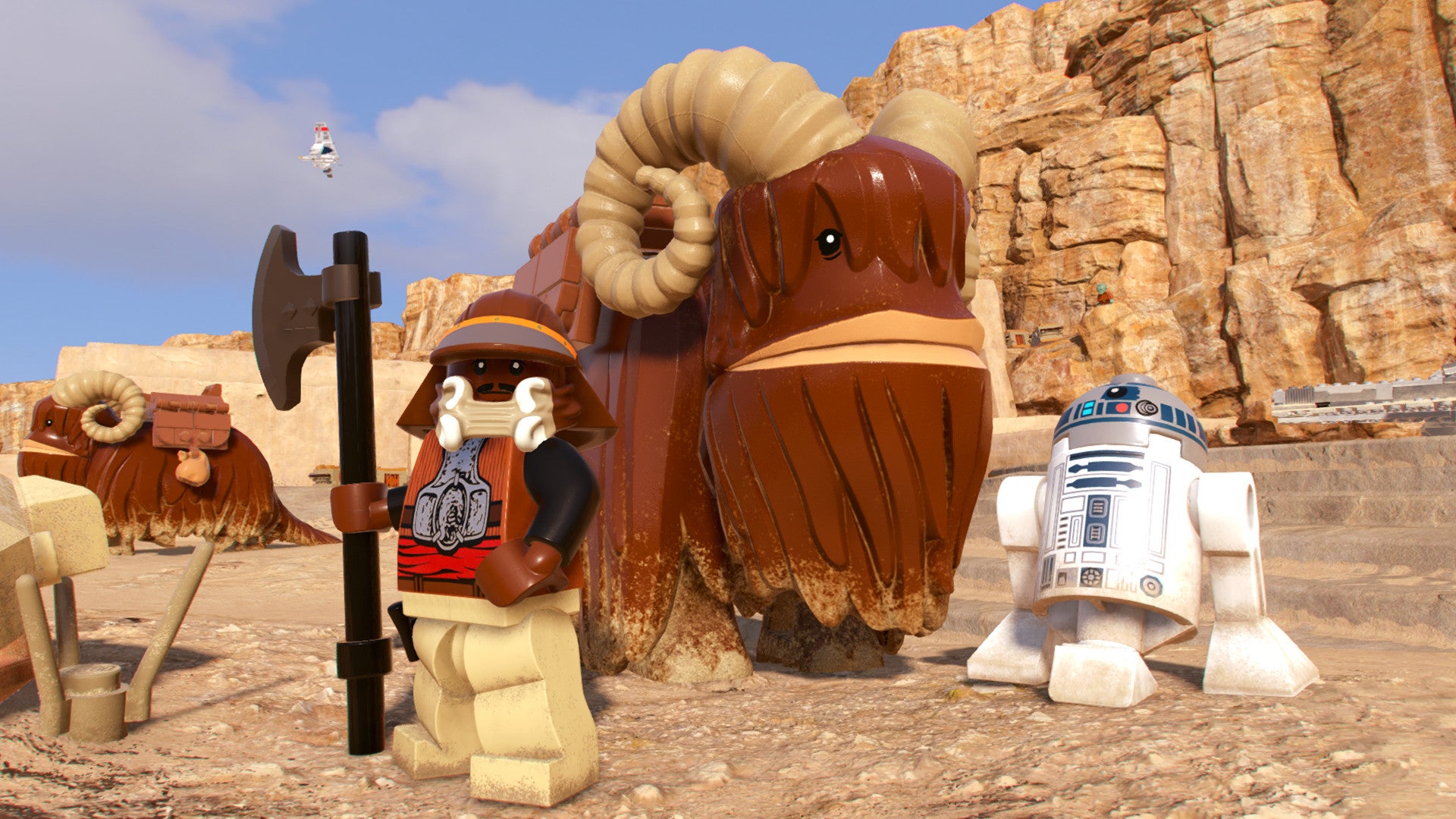 R2-D2 and an axe-wielding character flank a large buffalo-creature in Lego Star Wars: The Skywalker Saga.