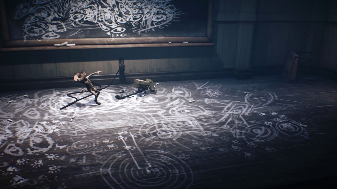 Mono from Little Nightmares II has just swung a lead pipe at a child made of porcelain and smashed its head; it was tied by a rope to the floor and drawing eyes in chalk on the walls and floor.