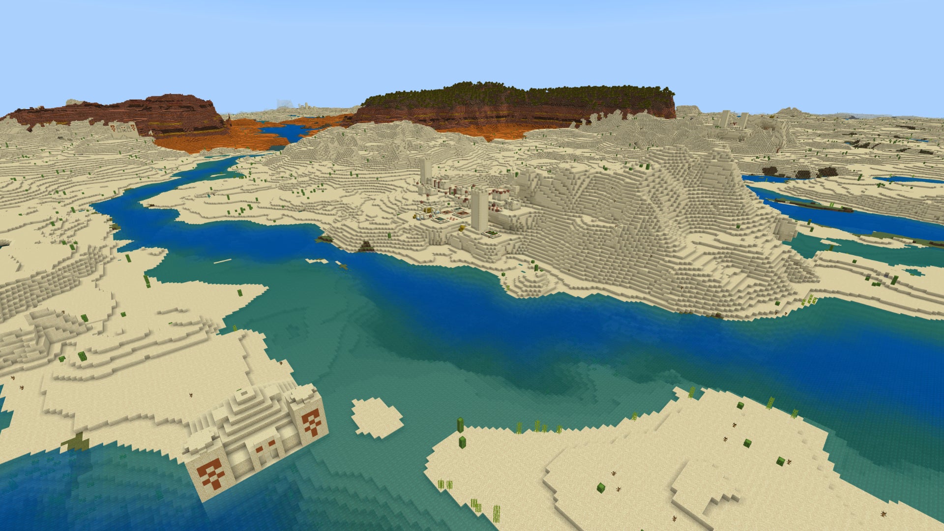 A Minecraft Bedrock landscape with desert and river in the foreground and badlands in the distance.