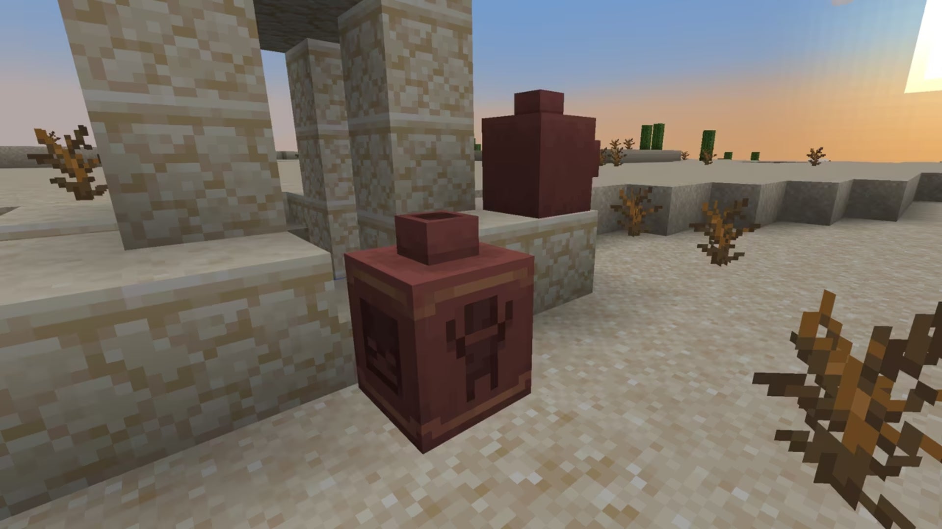 Two Minecraft Pots made out of excavated Pottery Shards near a sandstone build in a desert.