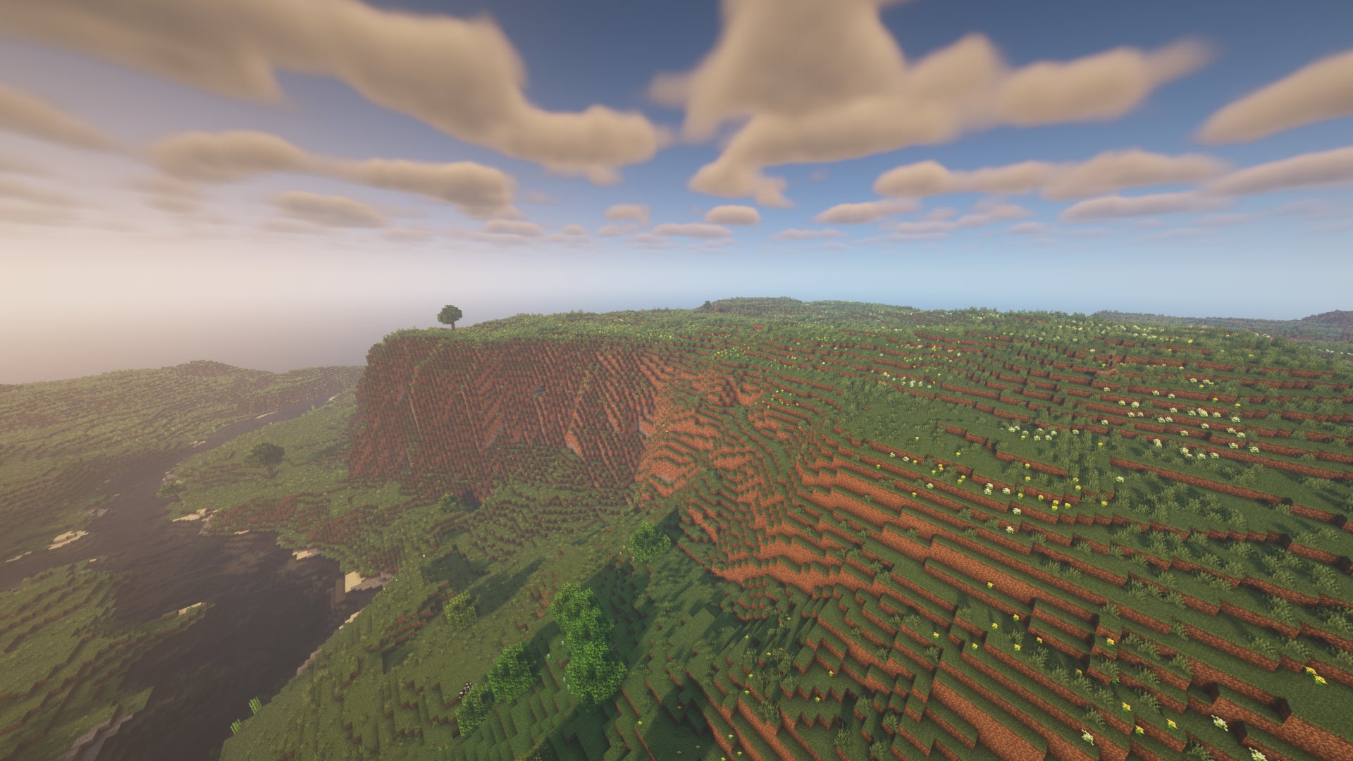 Un paysage Minecraft de falaises et de plaines, avec une rivière sur la gauche.