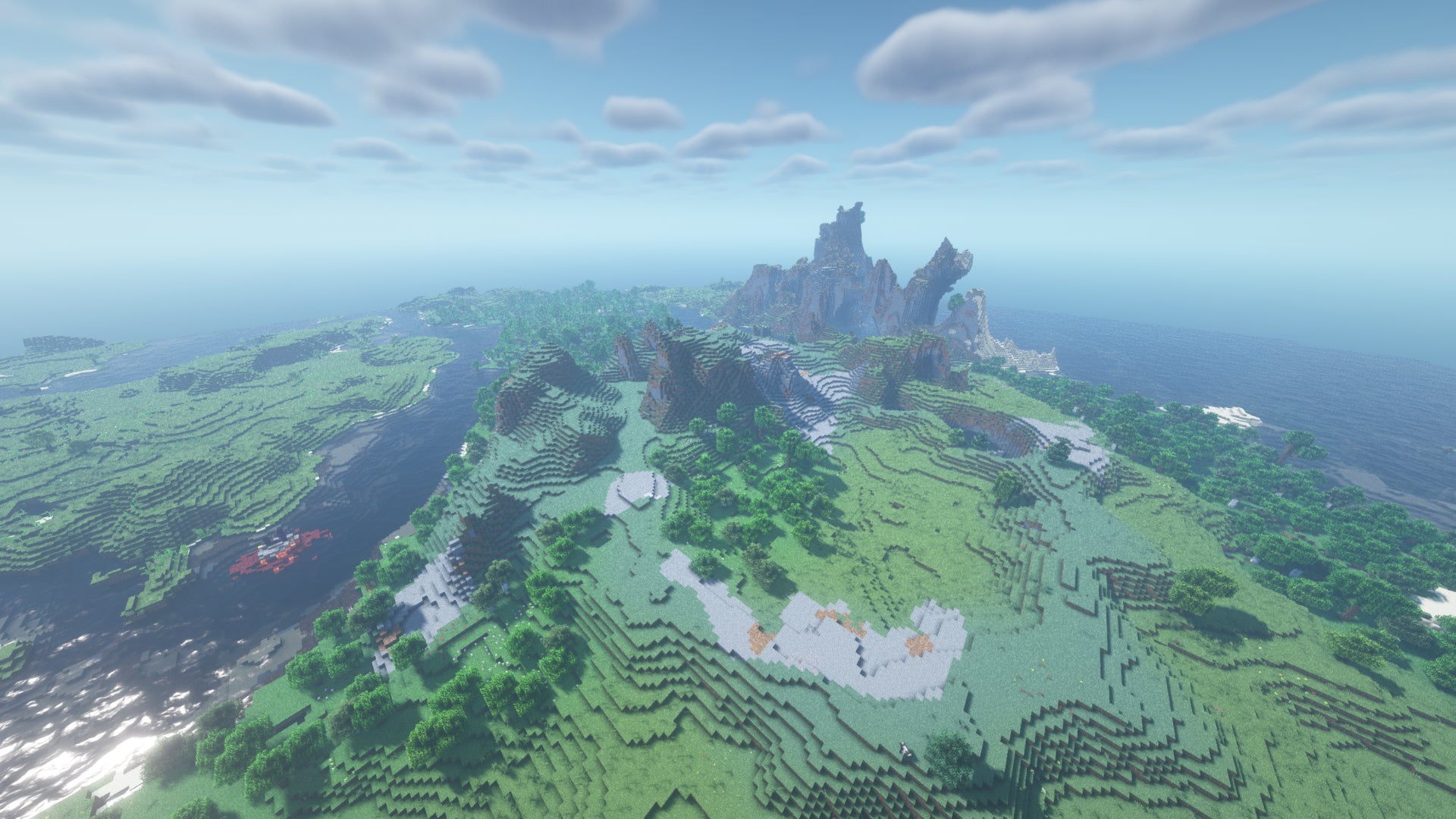 Un vaste paysage Minecraft de forêts, de collines et de plaines rocheuses, avec une chaîne de montagnes côtière au loin.