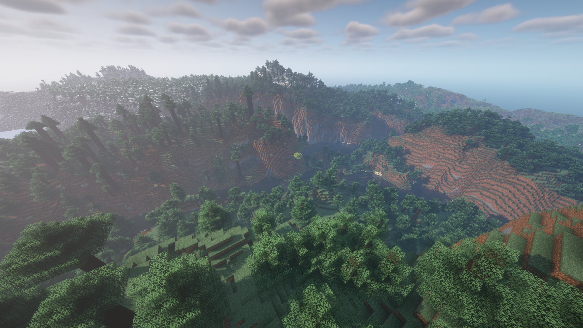 Un paysage Minecraft de collines et de vallées sinueuses couvertes de forêt.