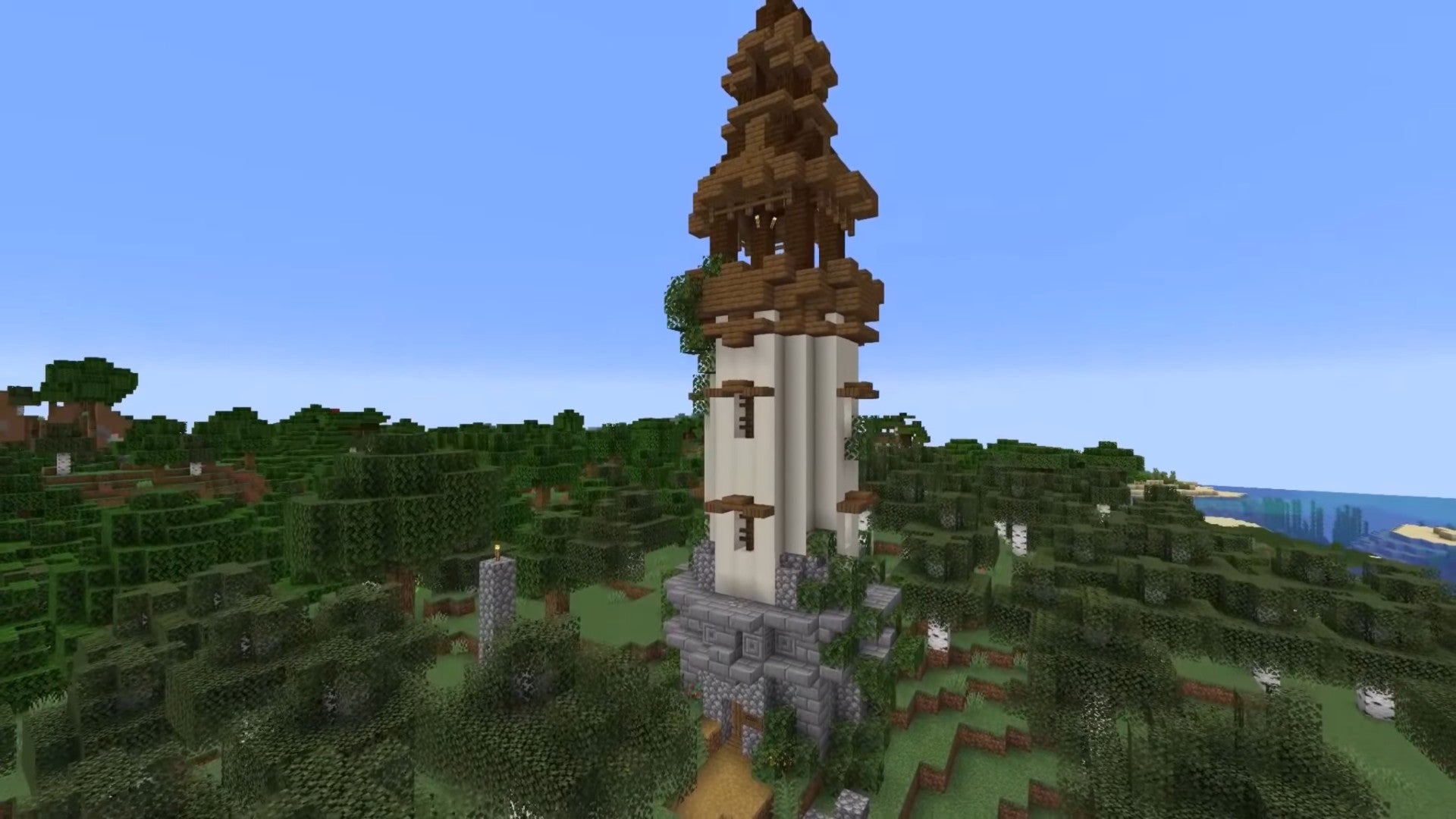 torre simple construida con piedra y madera que se eleva sobre un bosque en Minecraft
