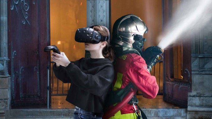 An image showing a firefighter and VR player back to back inside Notre-Dame cathedral.