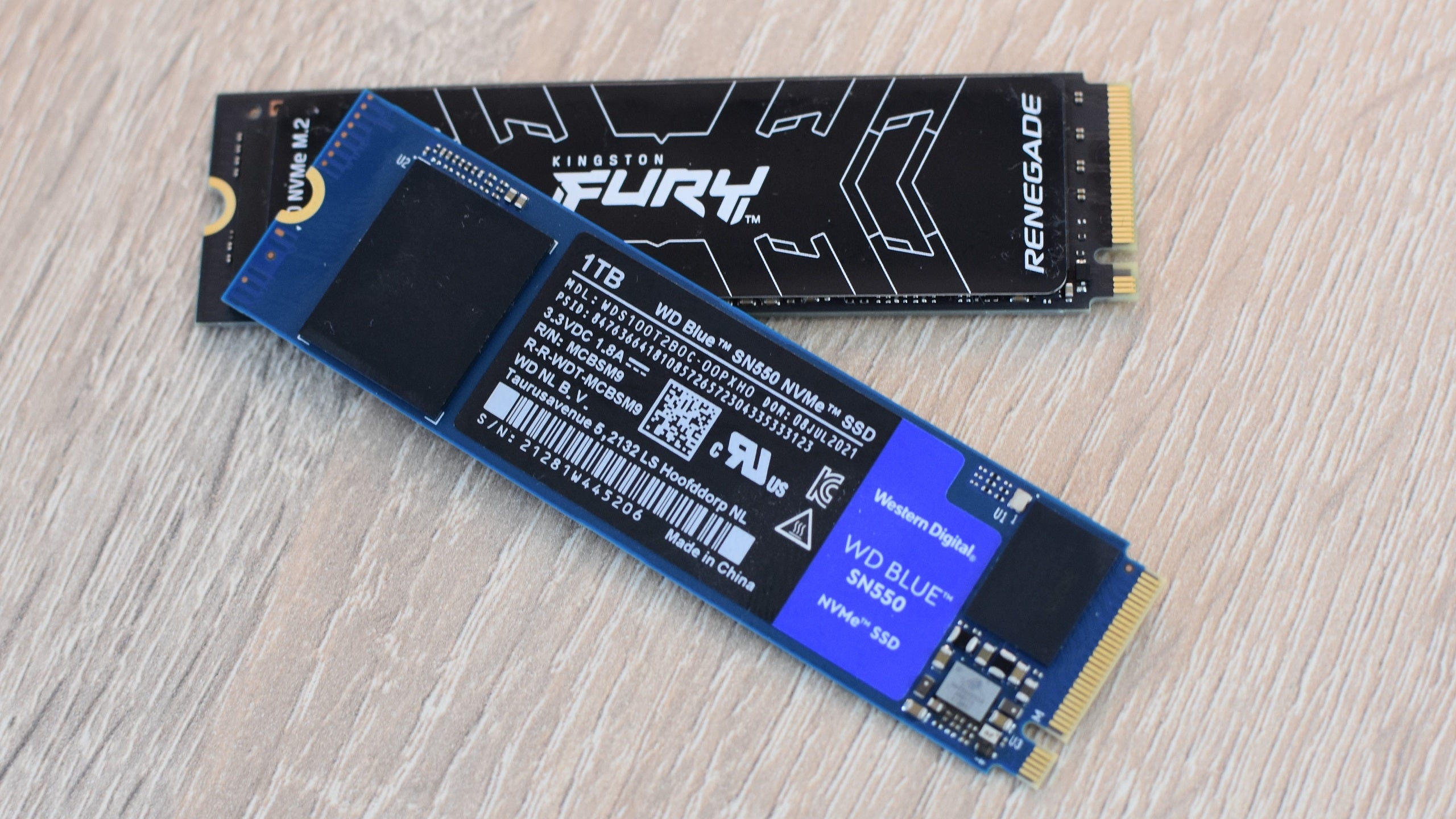 Two NVMe SSDs, the Kingston Fury Renegade and WD Blue SN550, on a desk.