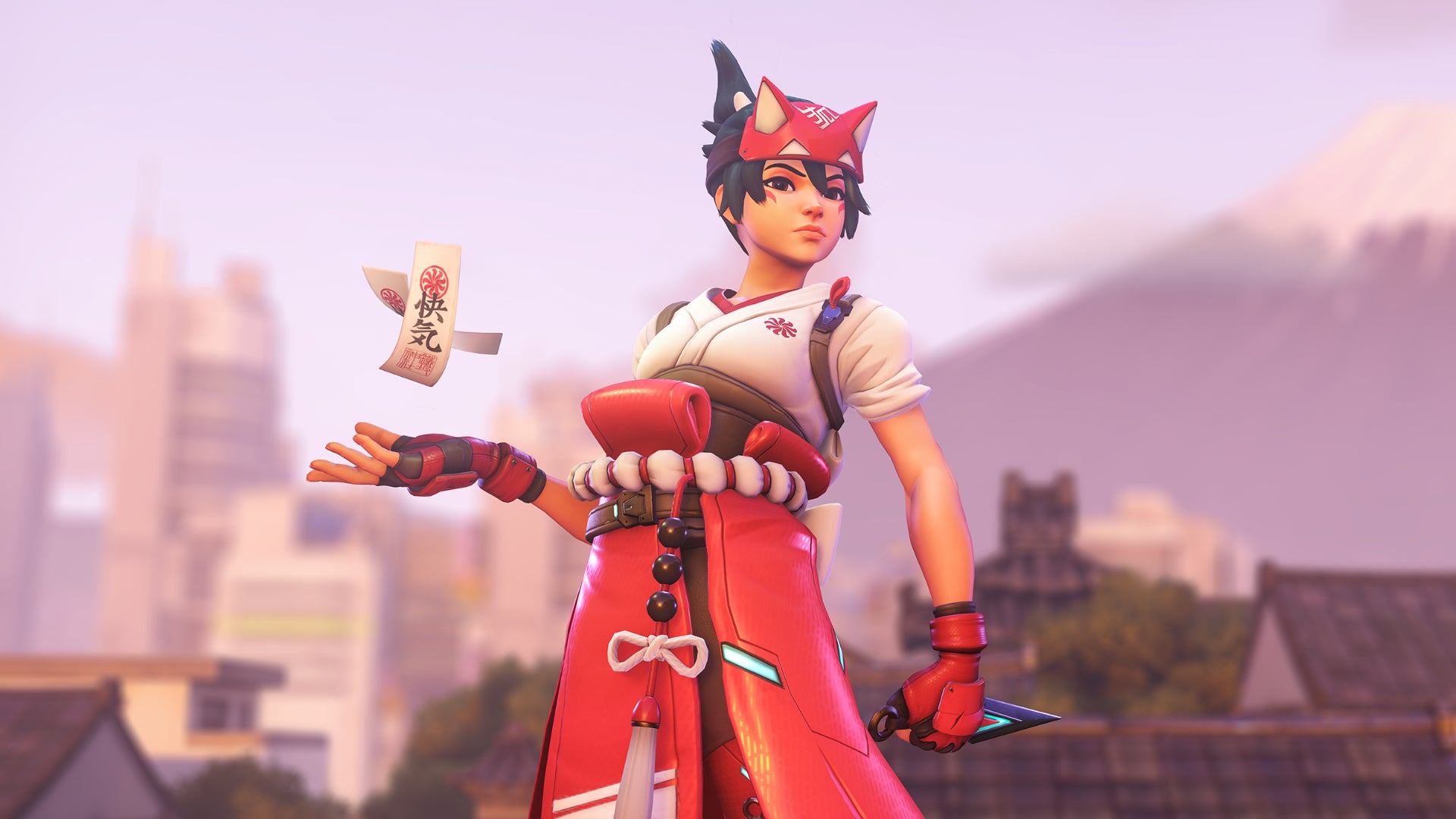Kiriko, a hero in Overwatch 2, stands before the camera with her Kunai in one hand and her Healing Ofuda floating above her other hand.