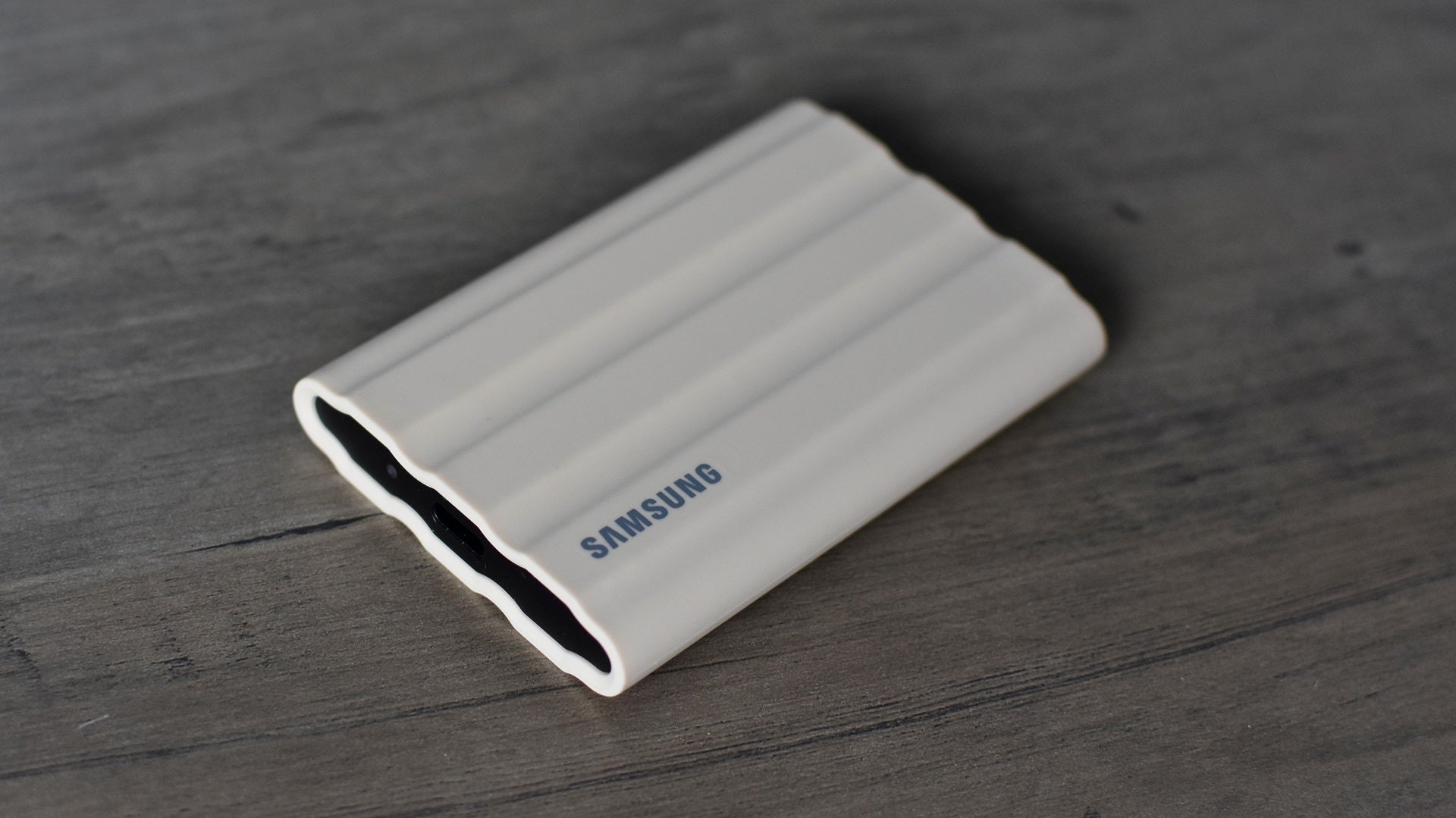 The Samsung T7 Shield portable SSD, without its detachable cable, on a table.