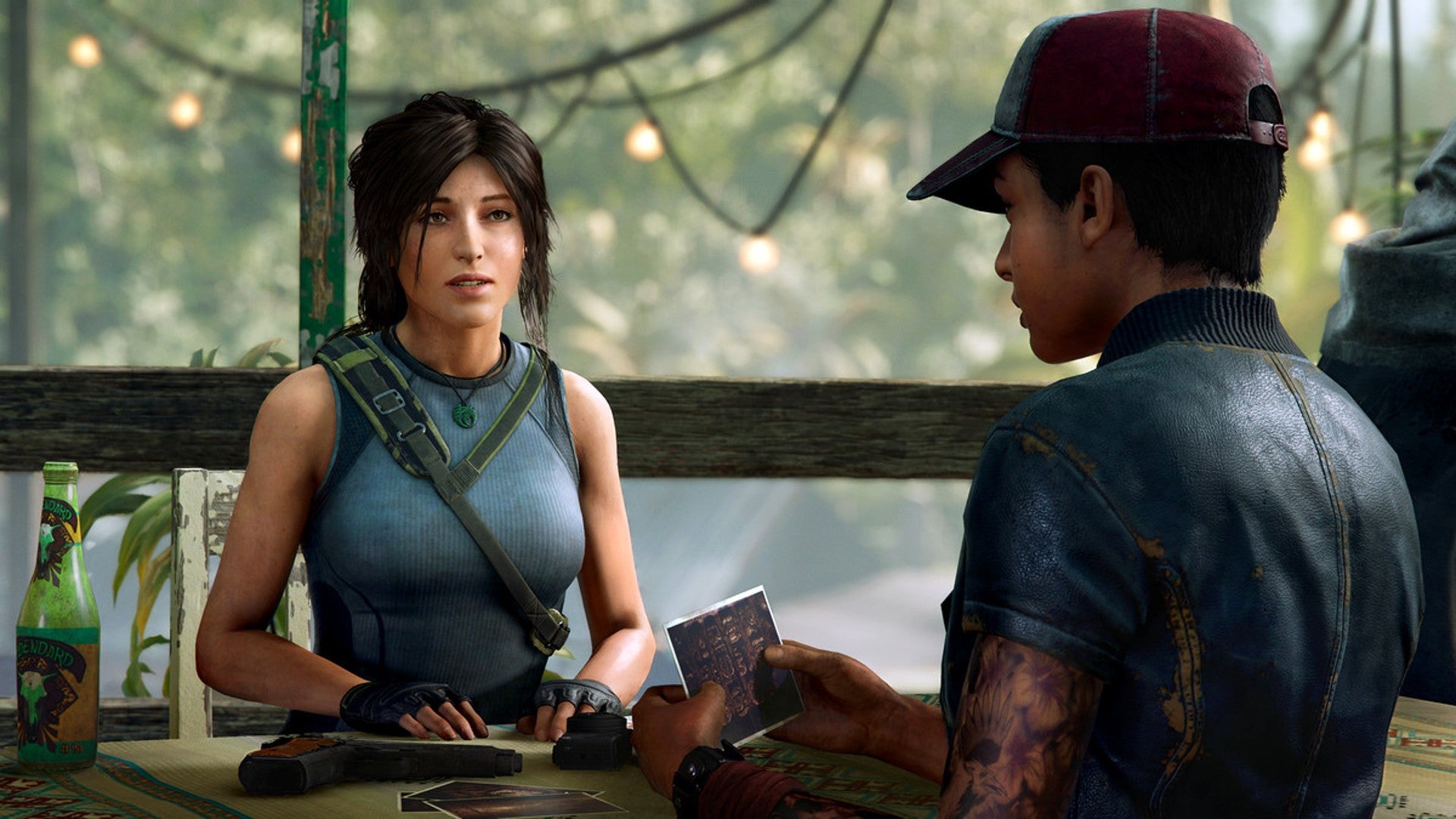 Lara Croft sits at a table having a conversation in Shadow Of The Tomb Raider