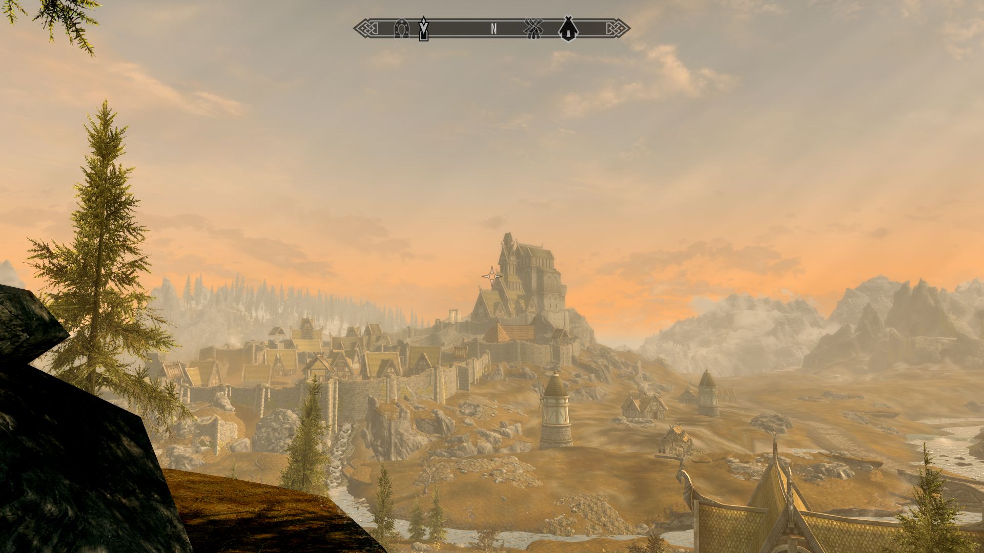Eine Abendansicht in The Elder Scrolls V: Skyrim während der goldenen Stunde, die die von Windmühlen umgebene Flachlandstadt Weißlauf zeigt