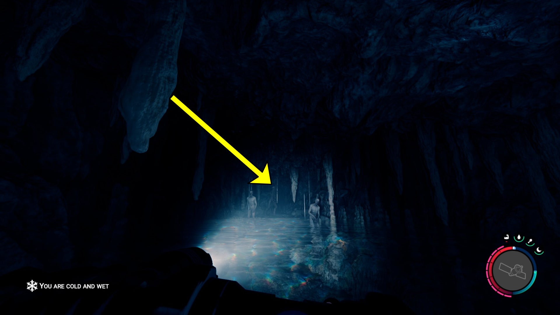 The player in Sons Of The Forest scouts a large group of mutants in a cave from the safety of a body of water.