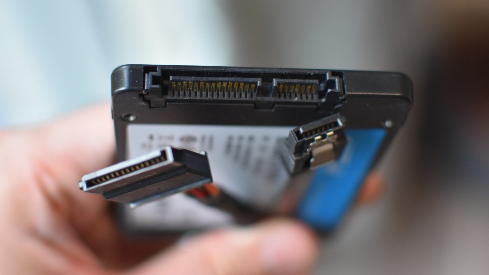 A 2.5in SSD's connection ports, held next to the corresponding power and data cables.