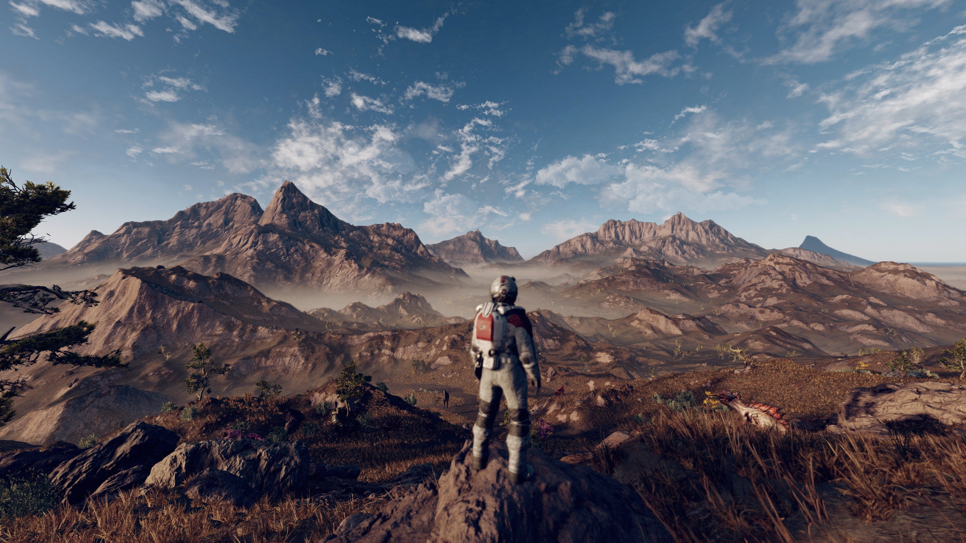 An explorer stands looking over a rocky planet in a Starfield screenshot.
