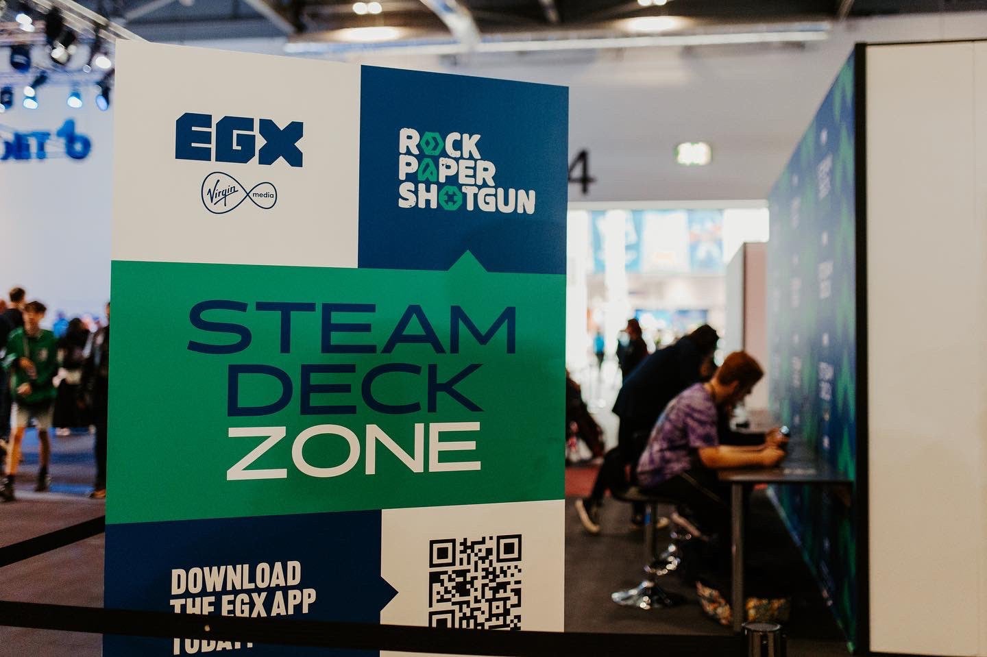A photo of people playing Steam Decks in the RPS Steam Deck Zone at EGX London 2022.