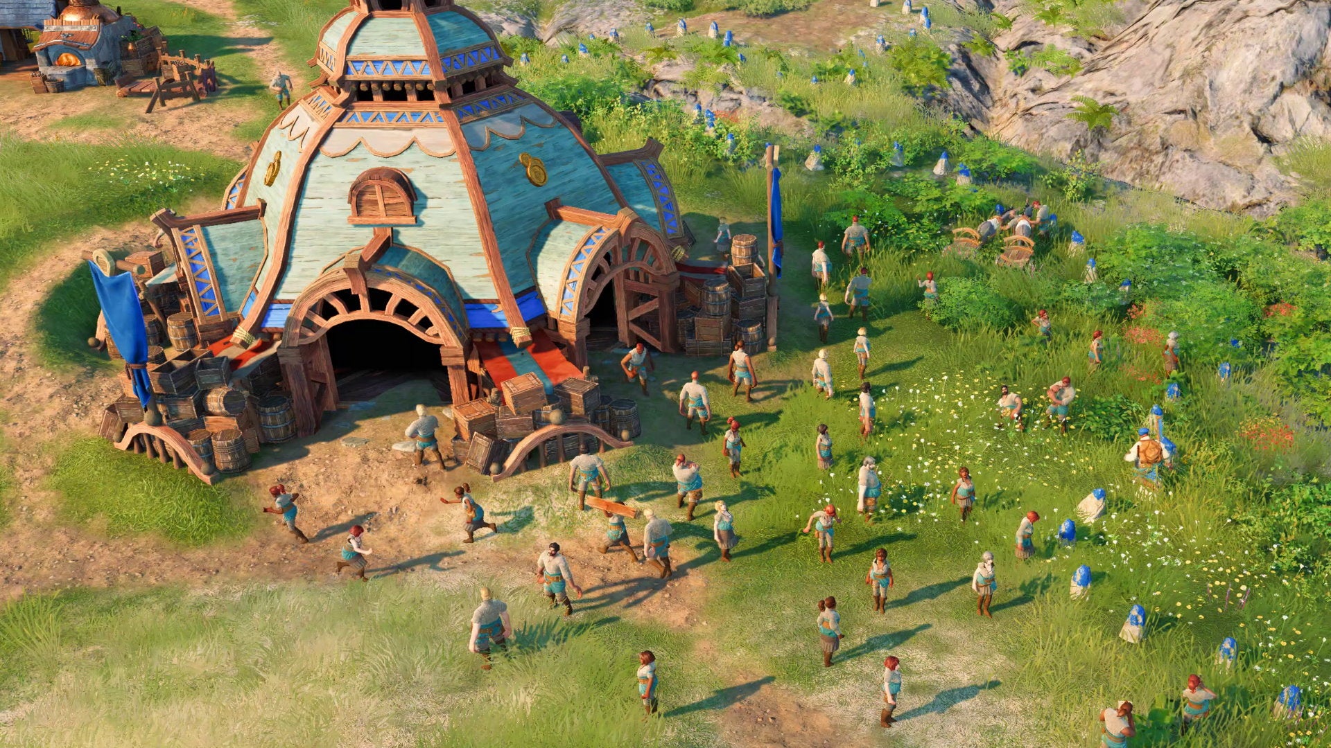 A group of villagers stand next to a large medieval warehouse in The Settlers