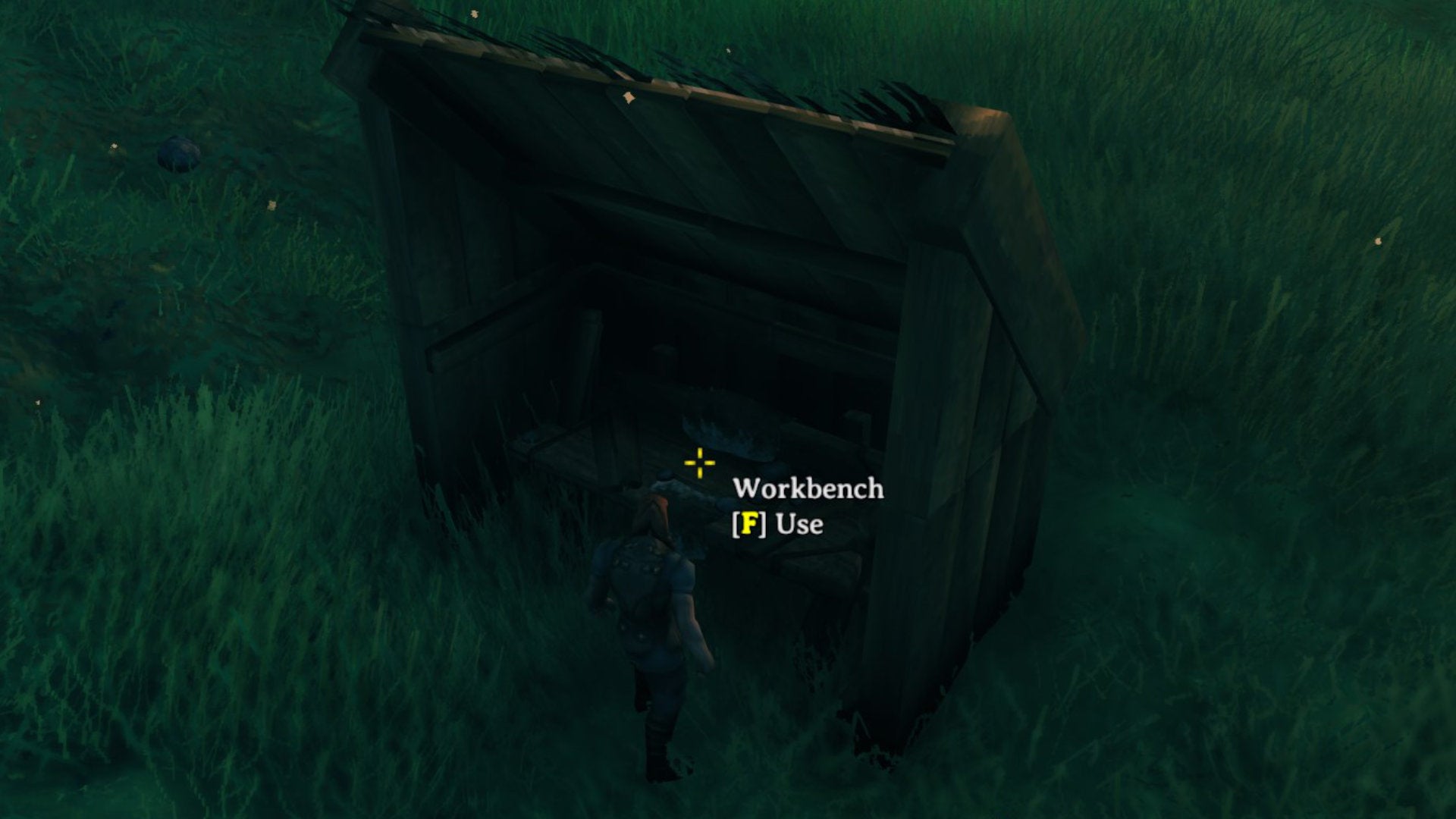 A Valheim screenshot of a fully covered and useable Workbench surrounded by 4 Wooden Walls and topped with two roof tiles and two triangle wall tiles.
