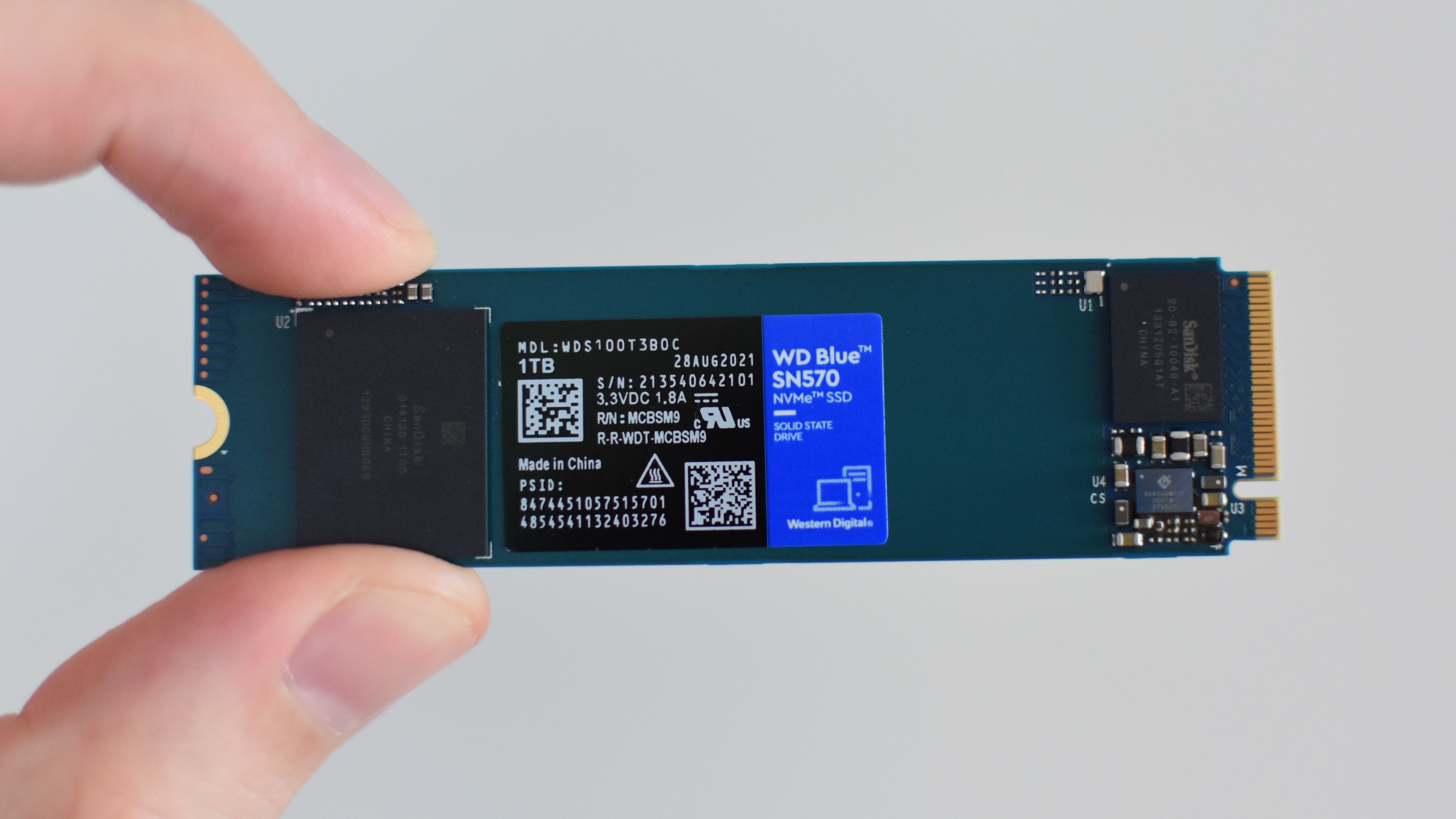 O SSD WD Blue SN570 sendo pressionado entre o polegar e o dedo.